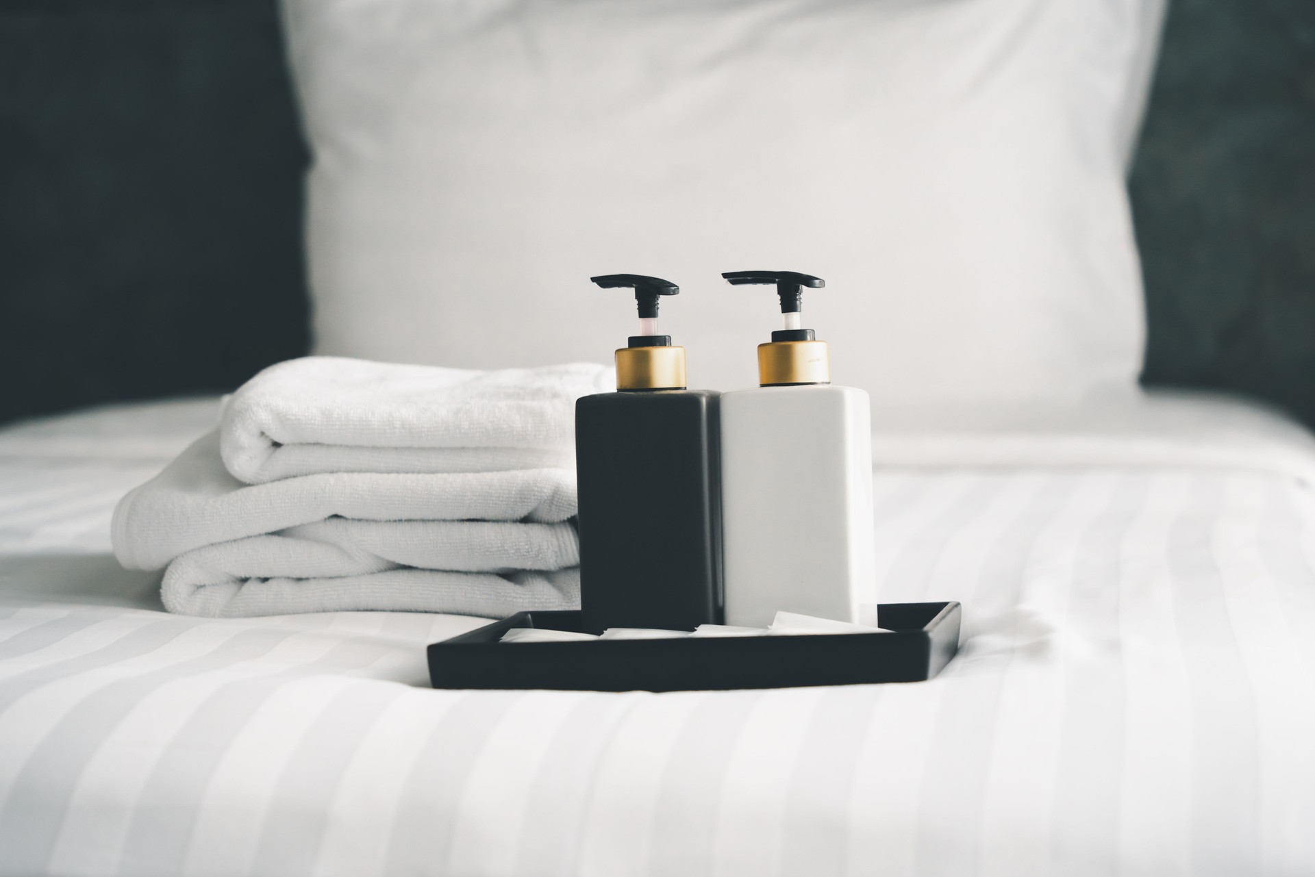 bouteilles d’accessoires de salle de bain sur lit blanc nettoyé dans la chambre d’hôtel, en flou artistique