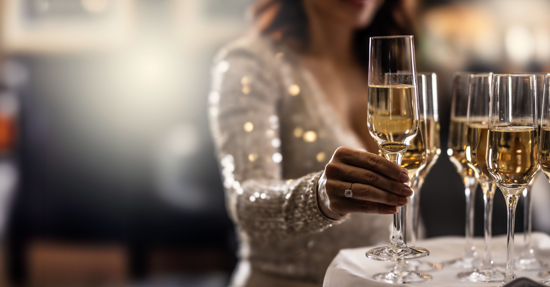 Un barman tient une assiette avec du champagne rose et une femme en robe de cocktail prend l’un des verres lors d’un événement, d’une fête ou d’un mariage.